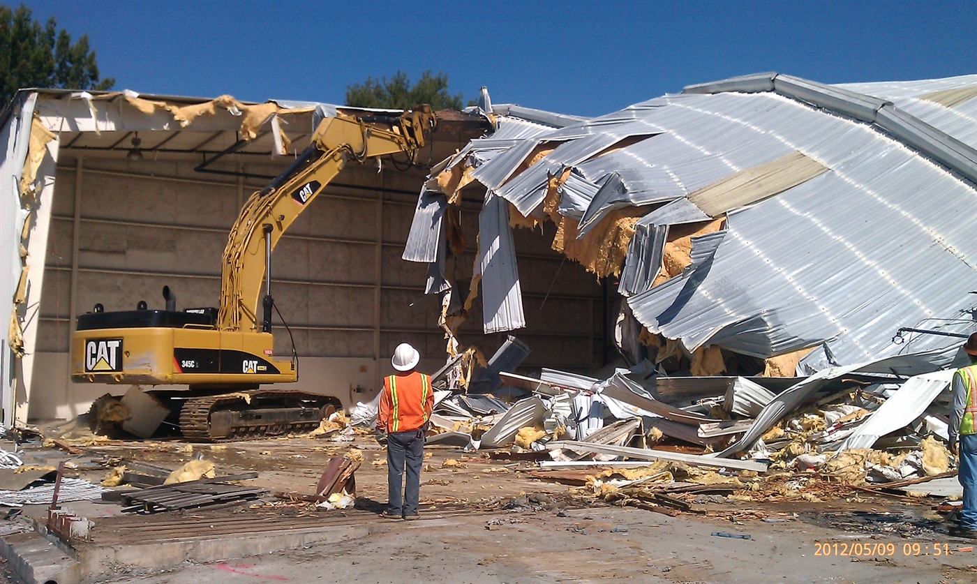 CAT excavator tearing into a commercial building's metal roof