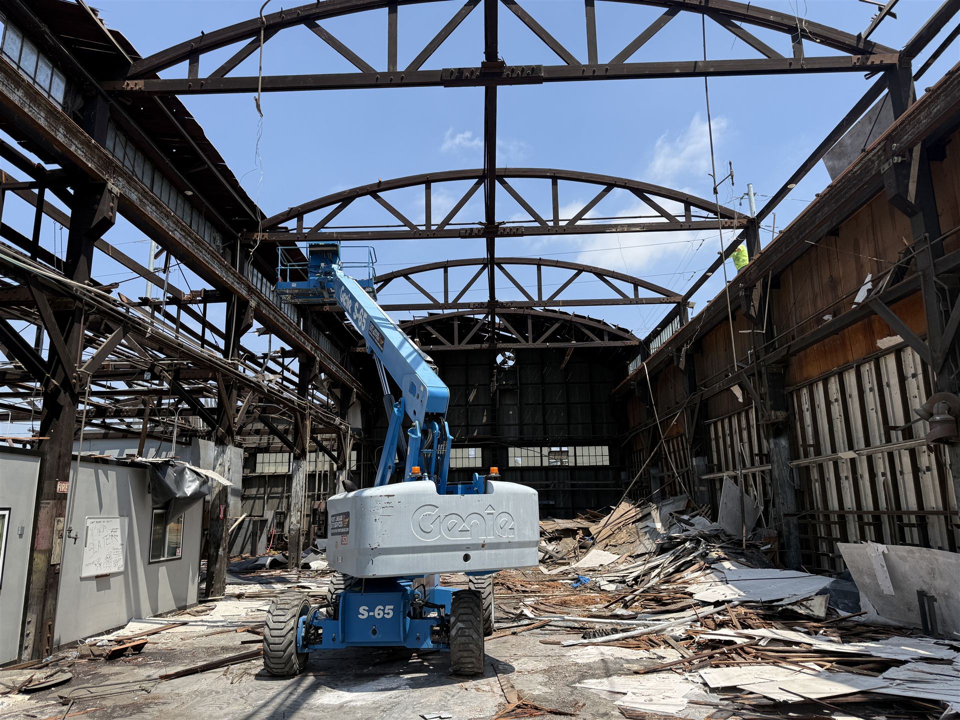 Excavator demolishing a building beneath a multi-level parking structure